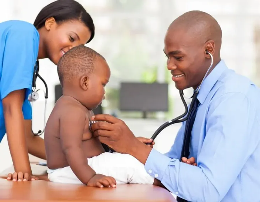 Family nurse practitioner working with nurse to take heart rate of pediatric patient